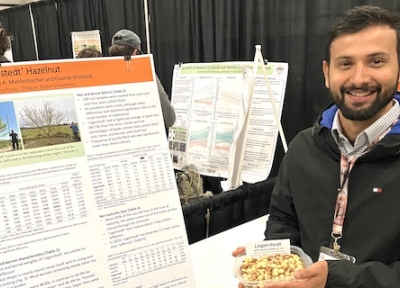 Gaurab Bhattarai, hazelnut breeder with Oregon State University, holds a bowl of Lagerstedt hazelnuts next to an explanatory poster about the new variety at the recent Nut Growers Society winter meeting in Albany, Ore. (Mateusz Perkowski/Capital Press)